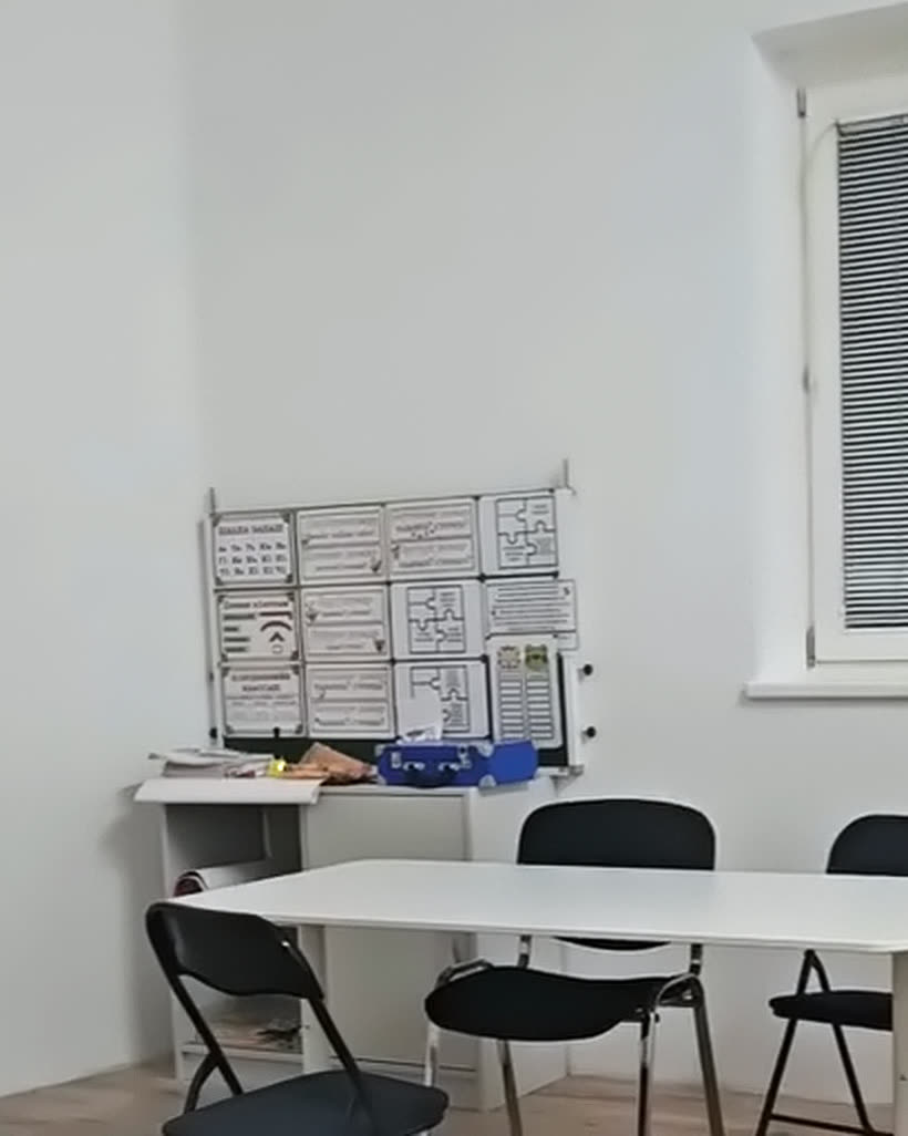 Klassenraum mit Fenster, Tischen und Lerntafeln